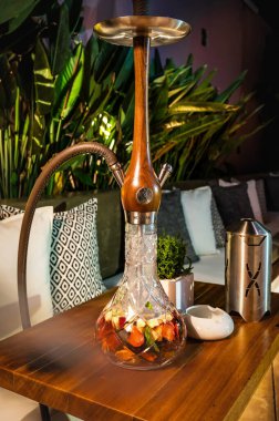 Heraklion, Girit, Yunanistan 06.12.2023. Lokanta masasında kullanıma hazır ahşap nargile. Rahatlatıcı bir deneyim için davet ayarları.  