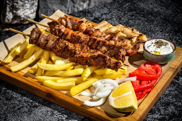 Close-Up Culinary Delight. A mouthwatering view of a wooden board adorned with grilled pork kebabs paired with golden French fries, this composition is ideal for food enthusiasts, barbecue lovers.