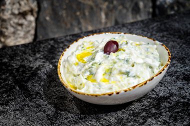 Çekici bir tzatziki sosu kasesinin yakın plan görüntüsü zengin ve kremsi dokusunu gözler önüne seriyor. Aşçılık tutkunları, Akdeniz mutfağı aşıkları ve yemek fotoğrafçılığı kavramları için mükemmel.