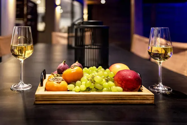 Romantic Evening Concept: Close-Up of Two Glasses of White Wine and Fruit Plate. Ideal for use in lifestyle publications, event promotions, and romantic-themed content.