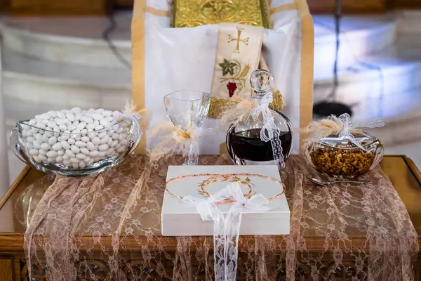 Greek wedding ceremony set in a church: Stefana wedding crowns, carafe with red sweet wine, common cup, honey with nuts, and koufeta sugar coated almonds. Selective focus