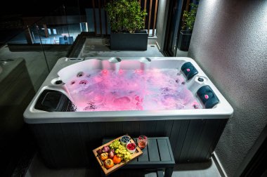 Rahatlatıcı Girdap Banyosu: Rose Water Light Ambiance ve yanında bir tabak taze meyve. Spa benzeri bir banyonun lüks ve rahatlatıcı deneyimini aktarmak için mükemmel.. 