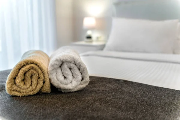 Close-Up of Two Rolled Towels on Bed: Elegant White and Beige Colors. Ideal for conveying a sense of comfort and luxury, perfect for use in home decor publications, hospitality promotions.