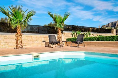 Sunny Villa Terrace: Rahat sandalyeler özel havuza bakıyor ve güneşli bir günde sakin bir atmosfer yaratıyor. Bu güneşli teras, villa konsepti için mükemmel bir rahatlama ve lüks yaşam sunuyor.