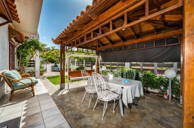 Kır evinin resimli arka bahçesi, sergilenen taş veranda. Veranda kırsal bir ahşap terasın altındaki büyüleyici bir yemek alanına kadar uzanıyor. Kırsal cazibe ve açık havada rahat yaşam