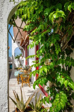 Görüntü, yemyeşil bir alana yerleşmiş huzurlu bir teras yakalıyor. Manzara canlı, yapraklı bitkiler tarafından çerçevelenmiş, mahremiyet ve sükunet hissi veriyor. Teras, dışarıda rahat bir şekilde donatılmıştır.
