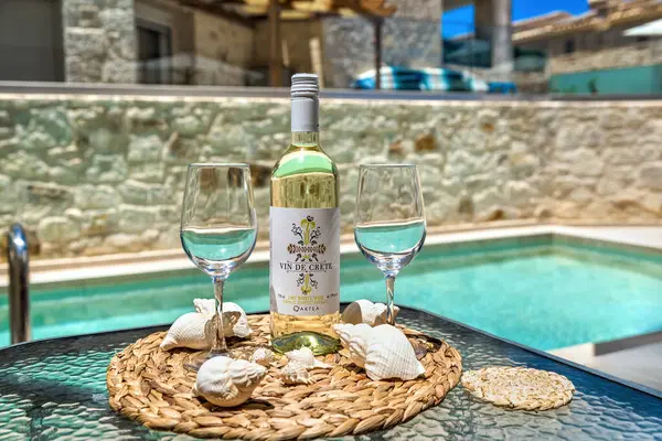 stock image beautifully set table featuring a chilled bottle of white wine, elegant wine glasses, with stunning swimming pool in the background. Creating visually appealing inviting scene