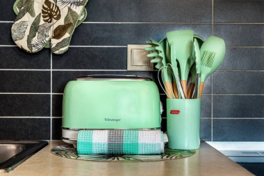 Mutfak köşesinde açık yeşil renkli tost makinesi ve bardakta mutfak gereçleri var. Çekici kurgu, retro stili taze, pastel bir renkle birleştirir.