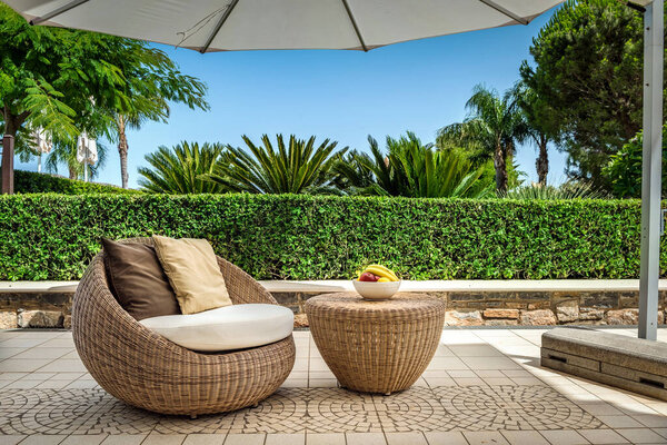 Cozy backyard featuring elegant rattan furniture, including armchair and table, served with fruits. Outside interior design combining comfort and style.Rattan furniture adds touch of sophistication.