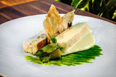 Üstü beyaz soslu, yeşil soslu beyaz et içeren iyi düzenlenmiş, şık bir restoran yemeği. Zarif sunum, canlı yeşil ve narin beyaz sos arasındaki farkı vurguluyor