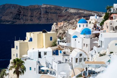 Views of Santorini. Stunning hillside covered with whitewashed houses, some adorned with iconic blue domes, cascading down towards sea. Traditional Cycladic architecture  clipart