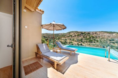 Sonsuzluk havuzu, şezlongları ve dağlara ve denize bakan şemsiyesi olan lüks bir tatil köyü. Akdeniz yaşam tarzı, rahatlama ve manzaralı tatil atmosferini ön plana çıkaran Idyllic yaz kaçışı.