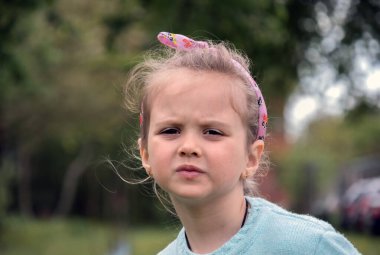 5-6 yaşlarında, doğanın arka planında kahverengi büyük gözleri olan güzel bir kızın yakın plan portresi.