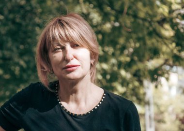 Orta yaşlı Avrupalı kadın, doğanın arka planına karşı, güzel gülümseyen bir bayanın yakın plan portresi.