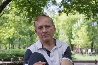 Çekici Avrupalı erkek, 50-60 yaşlarında, bahçenin arka planında yakın plan portresi