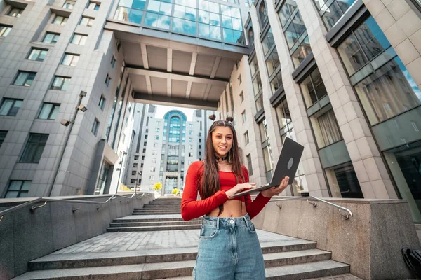 Sokaktaki güzel genç kadın ve bilgisayar laptopu kullanarak çalışıyor.