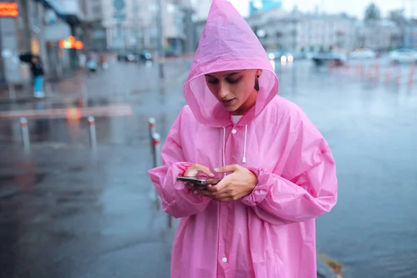 Yağmurluk Giymiş Genç Bir Kadın Yağmurda Birini Bekliyor — Stok fotoğraf
