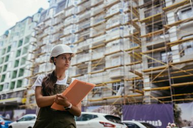 İnşaat işçisi kadın inşaat sektöründe güvenlik önlüğü takıyor. Kadın inşaat mühendisi konsepti