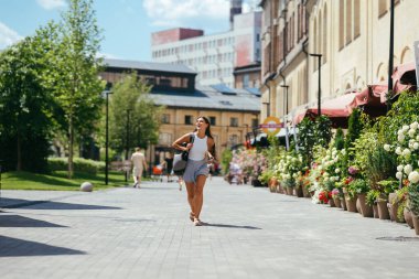Şık sırt çantalı genç hippi kadın bahar günü bir binanın etrafında dolanıyor. Güzel kız seyahat eder.