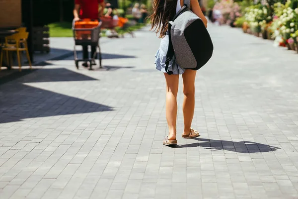 stock image Urban young hipster woman with stylish backpack walks around the city near a building in the spring day. Pretty girl travels.