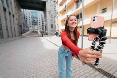 Young female blogger with smartphone streaming on the street. Close view