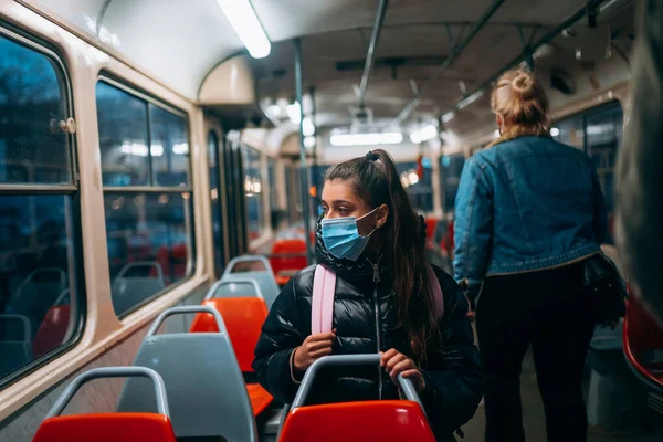 Young woman with mask traveling in the public transport by bus. Unique protective mask of the respiratory tract from coronavirus.