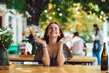 Arka plandaki yazlık kafede terasta kahve içen iki kız arkadaşın yakın plan portresi.