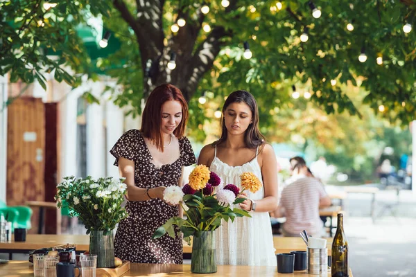 งสาวสองคนร งและท อดอกไม สวยงาม ดอกไม และช อดอกไม านกาแฟข างถนน จขนาดเล — ภาพถ่ายสต็อก