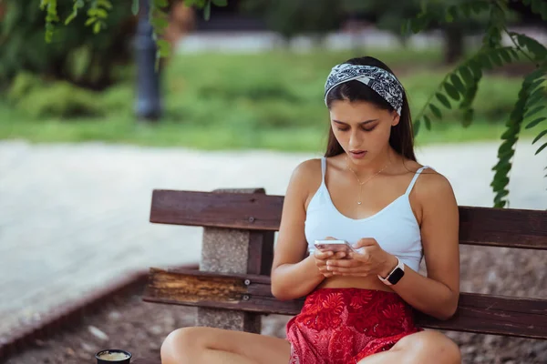 สาวท ความส สมาร ทโฟนในสวนสาธารณะ งบนเก — ภาพถ่ายสต็อก