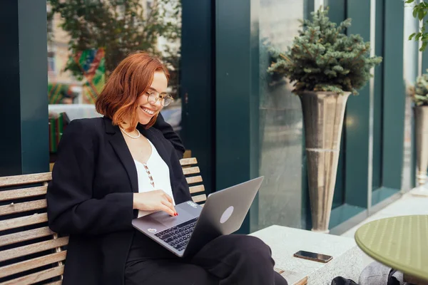 カフェ飲みコーヒーに座って入力ノートパソコンで働く豪華な魅力的な女性の写真 — ストック写真