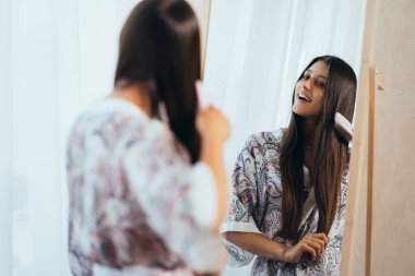 Aynanın önünde saçını tarayan bir kadın..