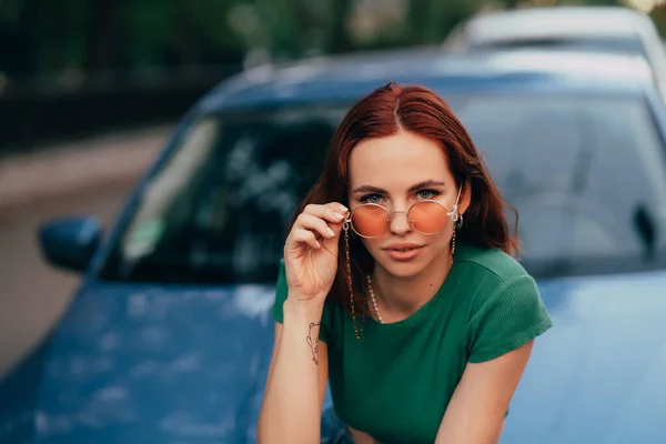 Güneş Gözlüklü Güzel Kız Mavi Bir Arabanın Kaputunda Oturuyor Yola — Stok fotoğraf