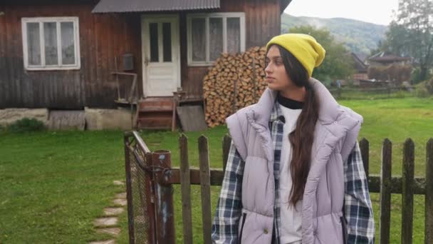 田舎の古い家を背景に美しい農民の若い女性 — ストック動画