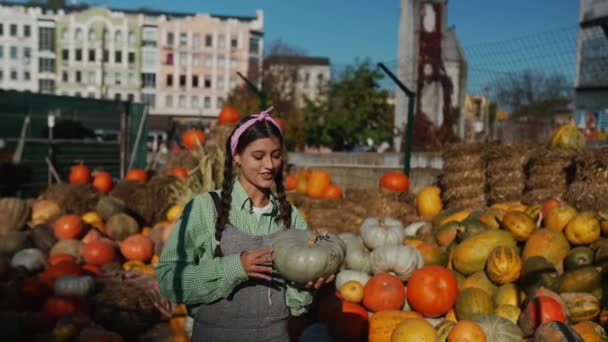 秋の収穫を背景に熟したカボチャを持つ幸せな女性農家 農業の概念 — ストック動画