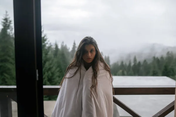 山のバルコニーの毛布に包まれた若い女性 — ストック写真