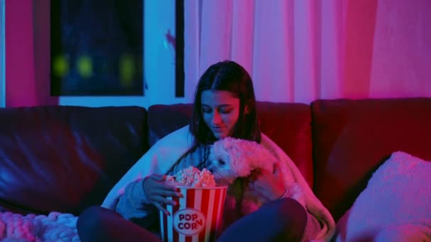 Молодая Девушка Развлекается Своей Мальтийской Собакой Сидя Диване Поедая Попкорн — стоковое видео