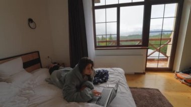 Yatakta yatarken dizüstü bilgisayarda çalışan kadın