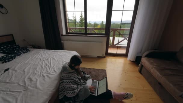 忙碌的年轻女性 带着笔记本电脑 靠双人床和关系网坐在地板上 或者只是在各个网站上消磨时间 — 图库视频影像