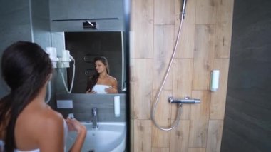 Banyodan çıktıktan sonra çekici genç bir kadın aynanın önünde duruyor..