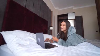 Yatakta yatarken dizüstü bilgisayarda çalışan kadın