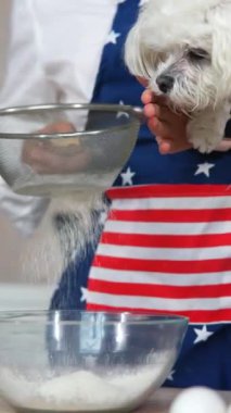 Mutfaktaki genç kadın, bir köpekle unu eşeliyor.