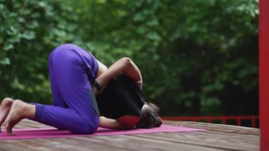 Verandada yoga yapan genç bir kadın.