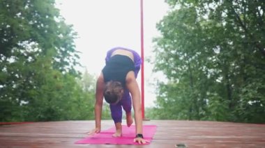 Verandada yoga yapan genç bir kadın.