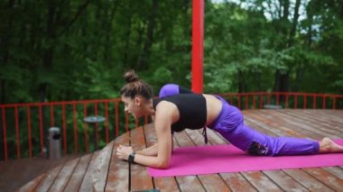 Verandada yoga yapan genç bir kadın.