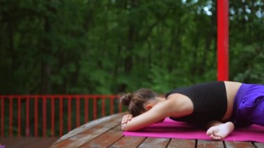 Verandada yoga yapan genç bir kadın.