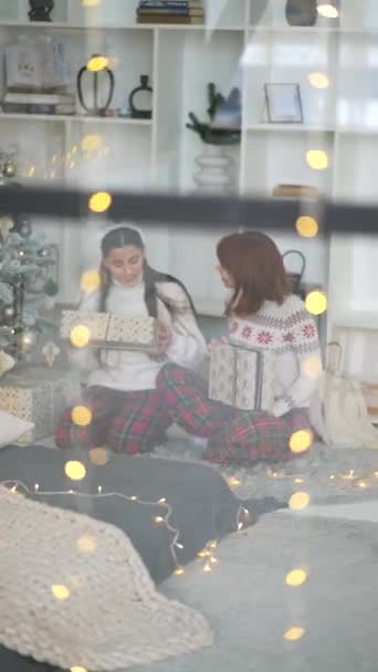 Kinézve Ablakon Két Barátnő Karácsonyi Ajándékokat Cserél Egy Karácsonyfa Mellett — Stock videók