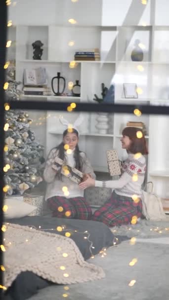 Looking Window Two Girlfriends Exchanging Christmas Presents Sitting Christmas Tree — Stock Video