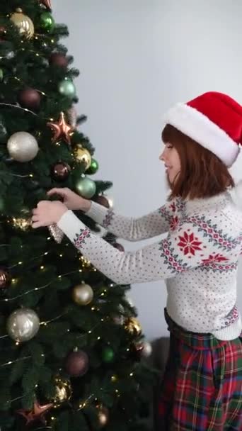 2人の若い女性がリビングルームのスタジオでクリスマスツリーを飾る — ストック動画