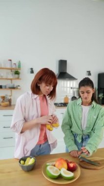 Genç kadınlar mutfakta taze meyve suyu yapmak için narenciye kesiyorlar.