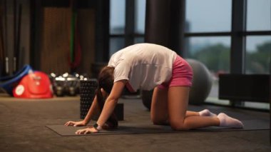 Bir kadın spor salonunda çalışmak için diz çöker..